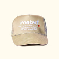 A khaki-colored trucker hat that reads: Rooted Plant shop and nursery. Est. 2018 - Brooklyn, NY